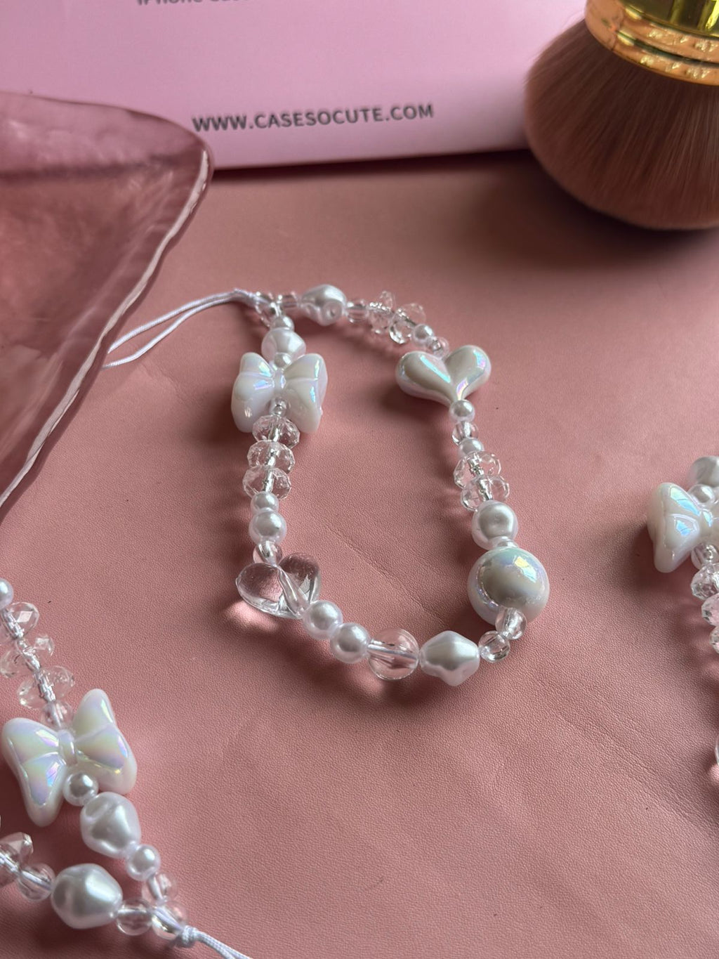 Close-up of the iridescent bow, heart and faceted clear beads on the Pearl Bow Phone Charm