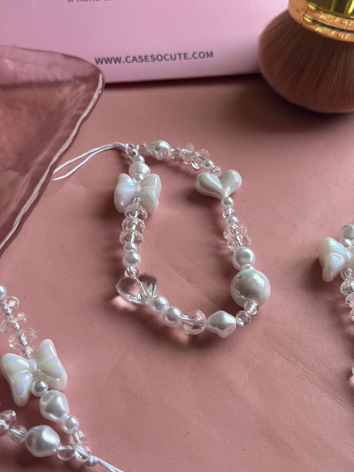 Close-up of the iridescent bow, heart and faceted clear beads on the Pearl Bow Phone Charm